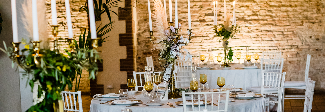 zona conviviale del Palmento del Maniero Country House, con tavoli rotondi apparecchiati, ricchi di allestimenti.